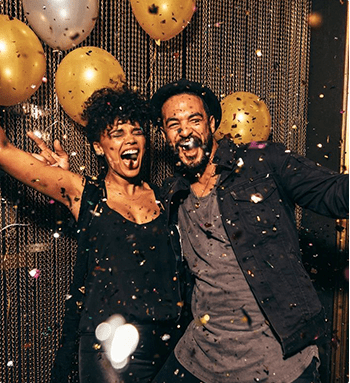 A man and woman are standing in front of balloons.