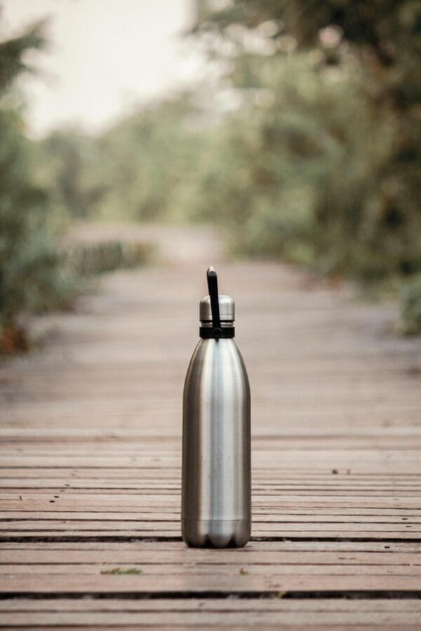 A silver water bottle sitting on top of a wooden floor.