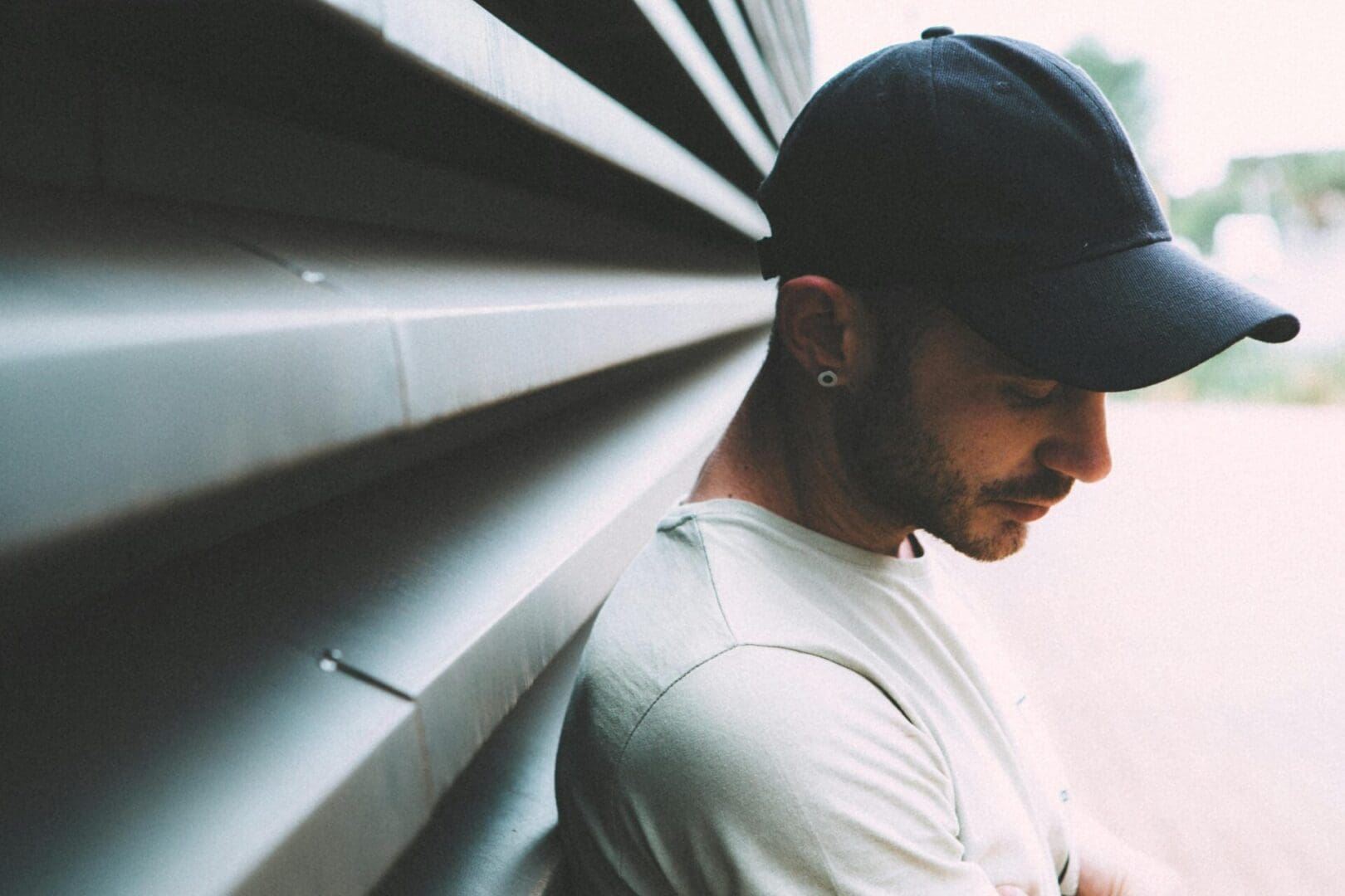 A man in a hat leaning against the wall.