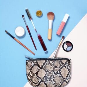 A snake print purse with makeup and brushes on it.