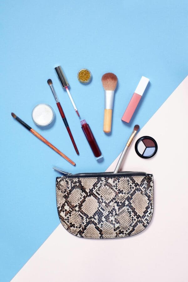 A snake print purse with makeup and brushes on it.