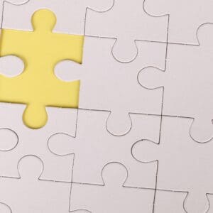 A yellow piece of puzzle sitting on top of a white jigsaw.