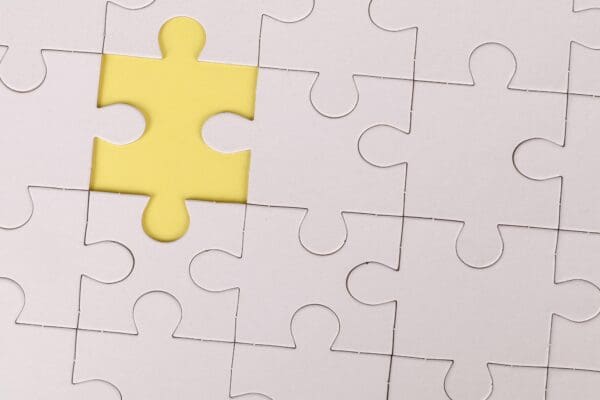 A yellow piece of puzzle sitting on top of a white jigsaw.