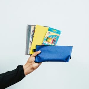 A person holding onto a blue bag with books in it