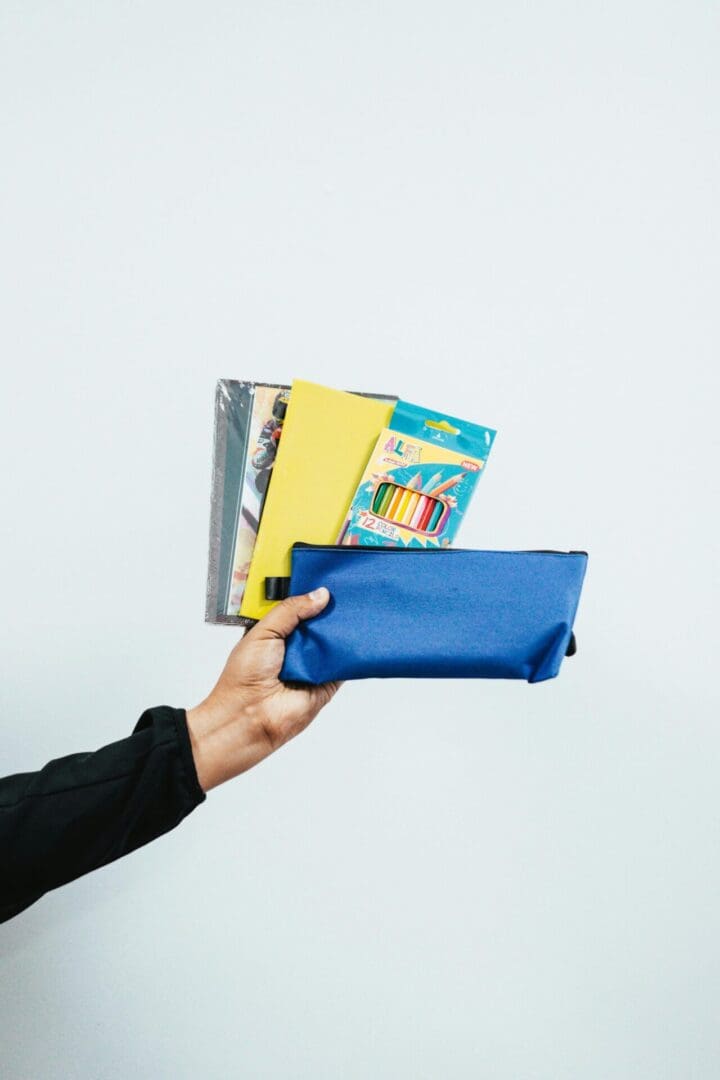 A person holding onto a blue bag with books in it